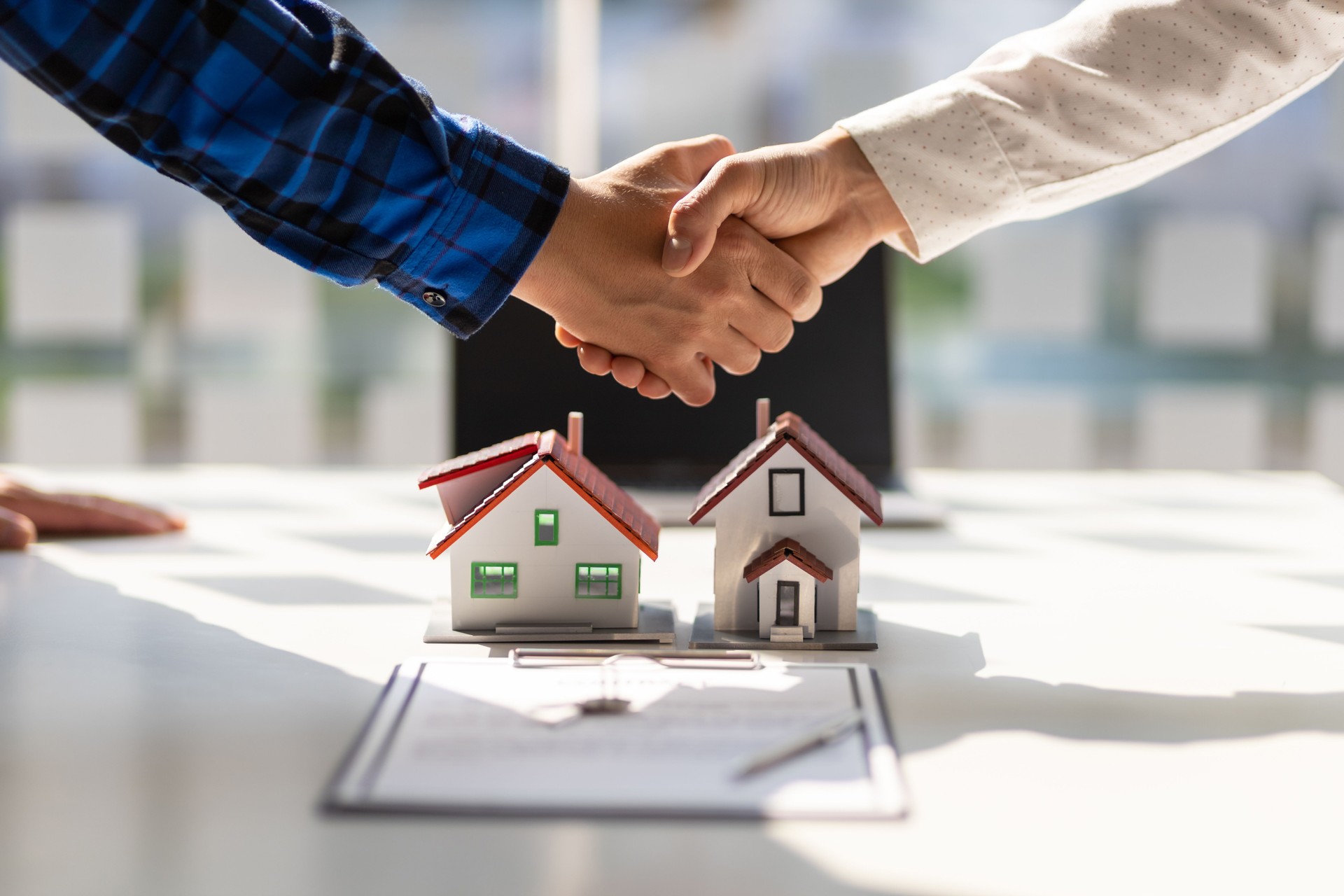 Immobilienmakler geben sich nach Abschluss der Vertragsunterzeichnung die Hand.